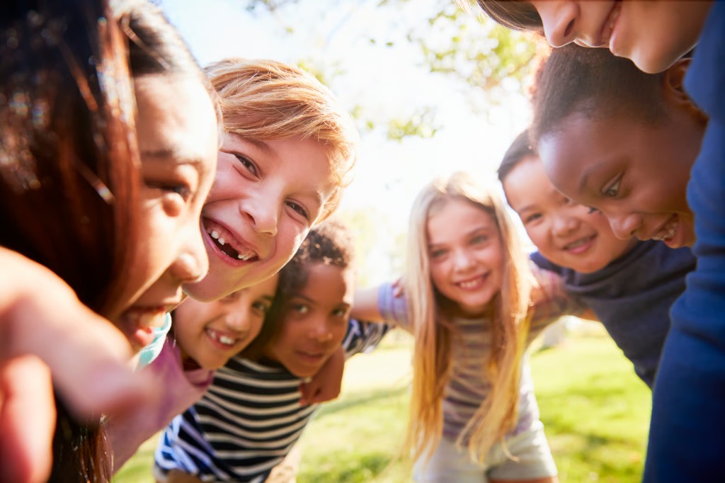 Children gathered together outdoors, smiling toward the camera
